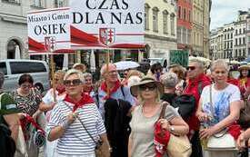 Seniorzy z Gminy Osiek na Senioraliach w Krakowie z transparentami. 