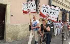 Seniorzy z Gminy Osiek na Senioraliach w Krakowie z transparentami. 