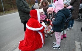 Pani Burmistrz Magdalena Marynowska w stroju śnieżynki częstuje dzieci cukierkami podczas Orszaku Świętego Mikołaja w Bukowej. 